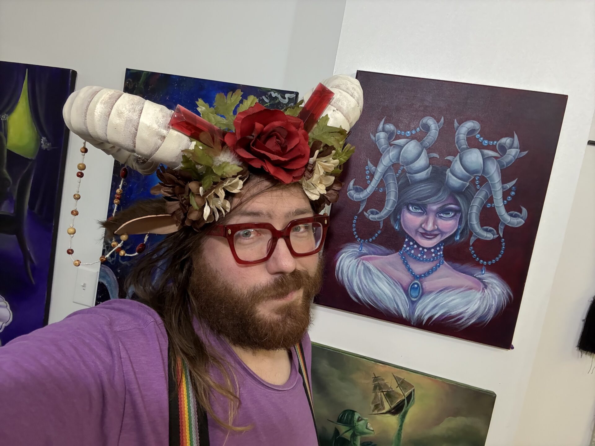 Author F. David Schultz wears a set of horns with a floral crown next to the painting that forms the basis of the book cover for Crown of Horns.
